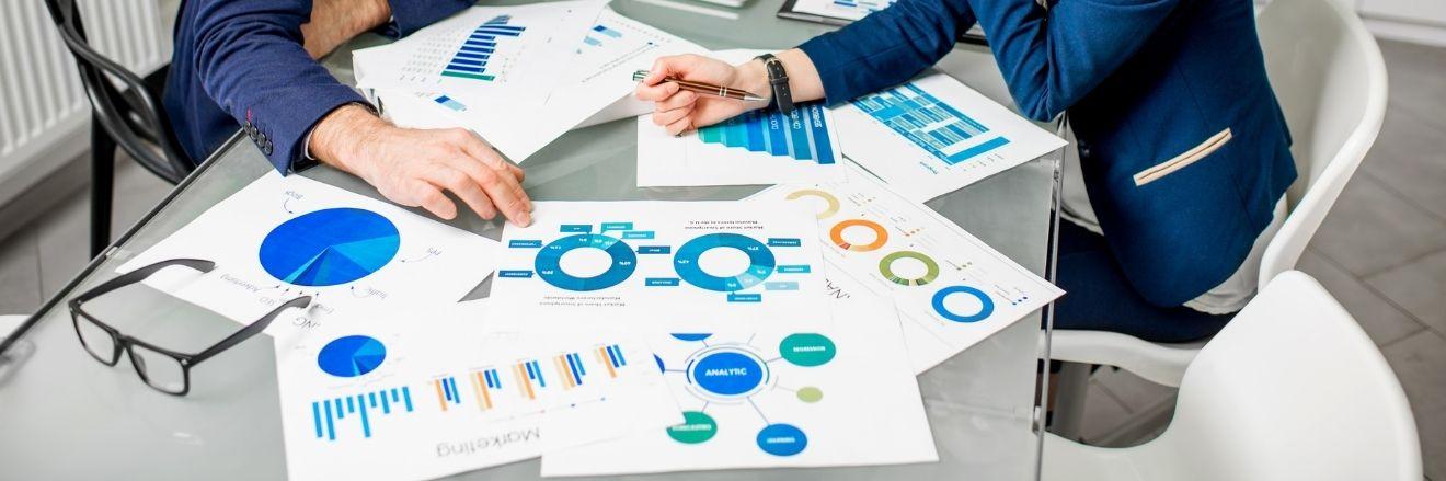 due persone lavorano a un tavolo dove sono collocati fogli con diagrammi e statistiche 